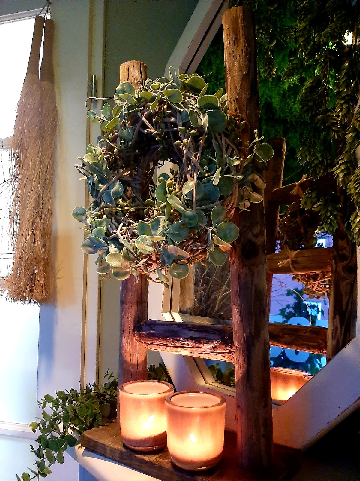 Eucalyptus-krans op een ladder van takken, met waxinelichten.